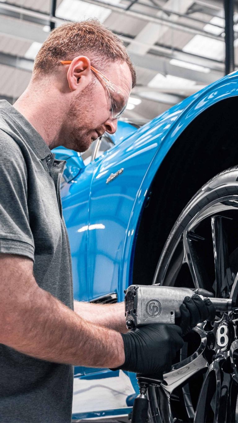 Bentley technician tightening front right wheel nuts of Bentley Continental GT Azure in Kingfisher By Mulliner colour